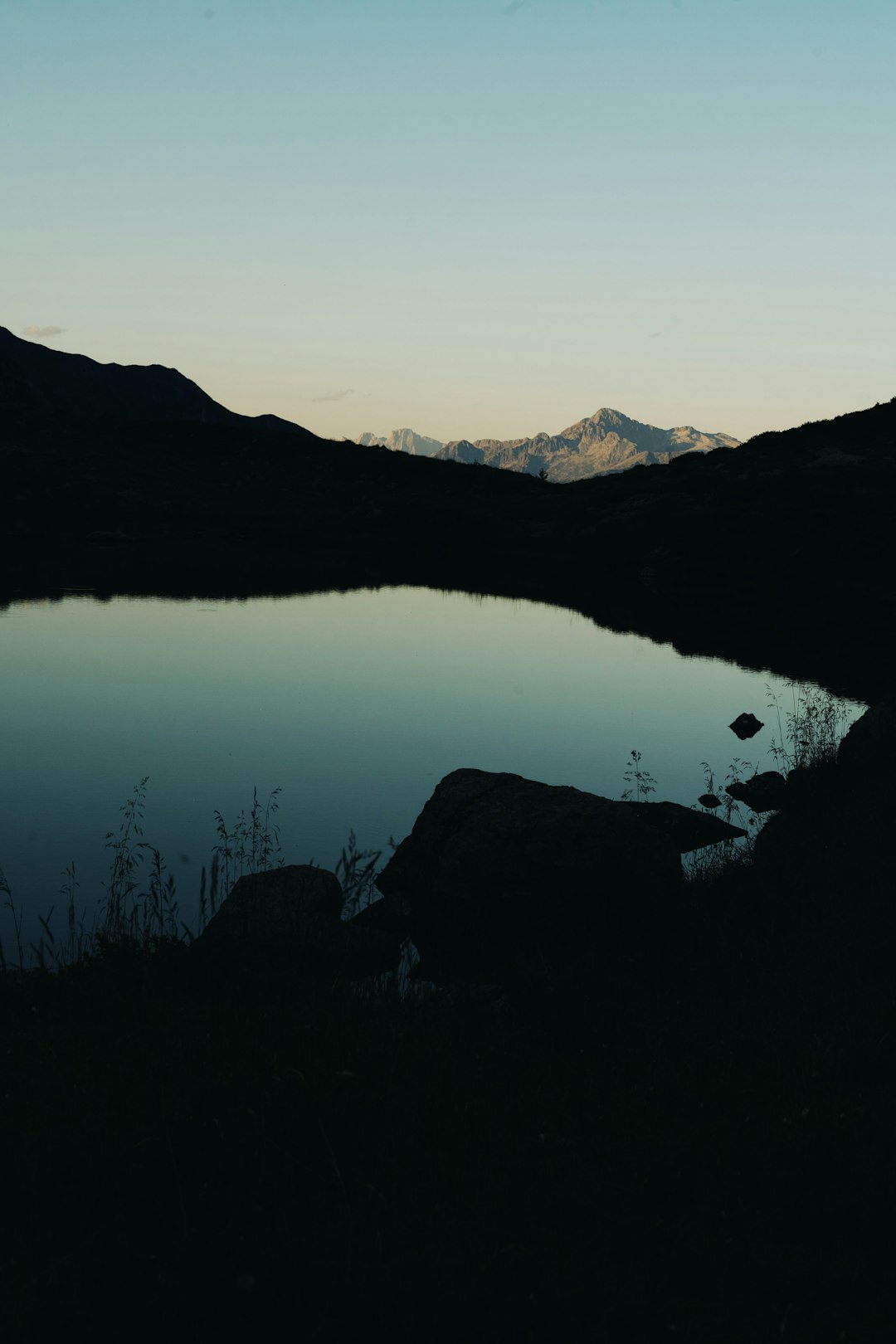 High-resolution tranquil mountain lake at dawn with distant snow capped peaks photo by Filippo Molinari in Featured | PictureHub